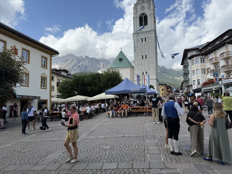 Platz im Zentrum von Cortina mit Kirchturm und Menschen beim Stadtbummel